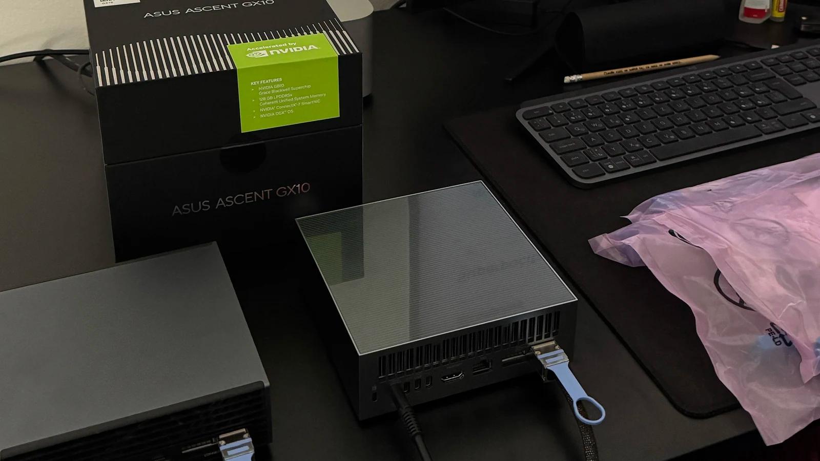 Krabice od třetího ASUS Ascent GX10 na stole, vedle už vybalený stroj a klávesnice